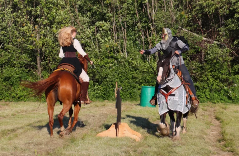 Two riders in costume, one on a chestnut horse and one on a caparisoned horse, take aim at a target at the 2026 Shediac Renaissance Faire